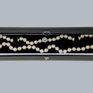 May include: A white pearl necklace with a silver clasp in a black velvet jewelry box.