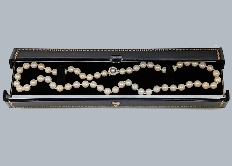 May include: A white pearl necklace with a silver clasp in a black velvet jewelry box.