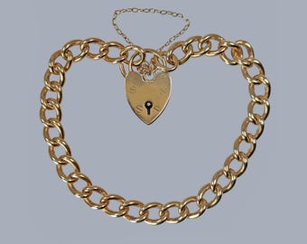 May include: A gold-colored bracelet with a heart-shaped padlock clasp. The bracelet is made of thick, rounded chain links. A smaller chain connects the padlock to the bracelet. The padlock has a keyhole and is detailed with subtle markings.