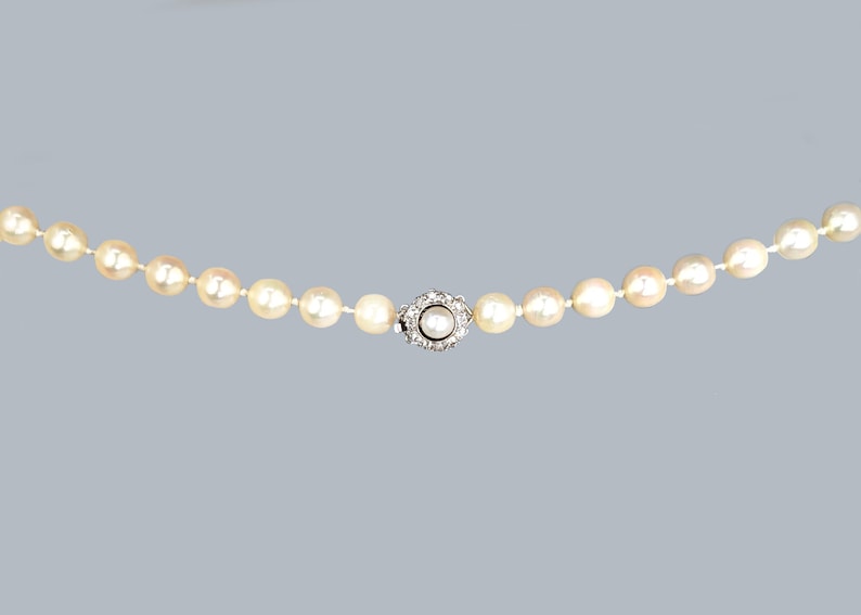 May include: A pearl necklace with a silver clasp featuring a small pearl surrounded by diamonds.