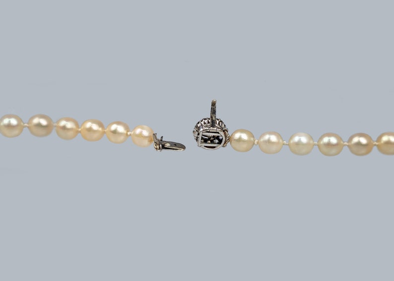 May include: A pearl necklace with a silver clasp. The necklace is open and the clasp is visible.