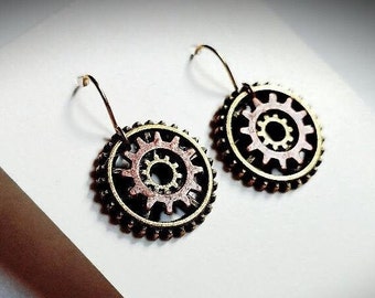 Peut inclure: Une paire de boucles d'oreilles en bronze avec un motif d'engrenage. Les engrenages sont superposés et ont une finition cuivre et or.