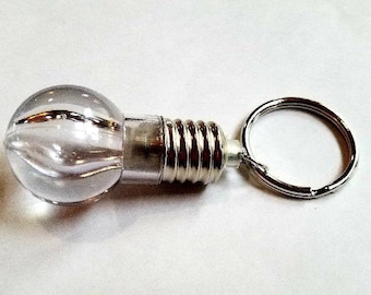 May include: A clear plastic light bulb keychain with a silver metal screw base and a silver metal ring.