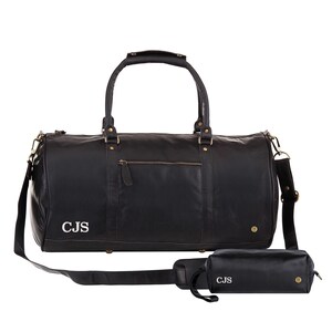 May include: Black leather duffel bag with a shoulder strap and a matching black leather toiletry bag. Both bags have gold hardware and are monogrammed with the initials "CJS".