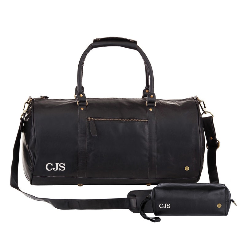 May include: Black leather duffel bag with a shoulder strap and a matching black leather toiletry bag. Both bags have gold hardware and are monogrammed with the initials "CJS".