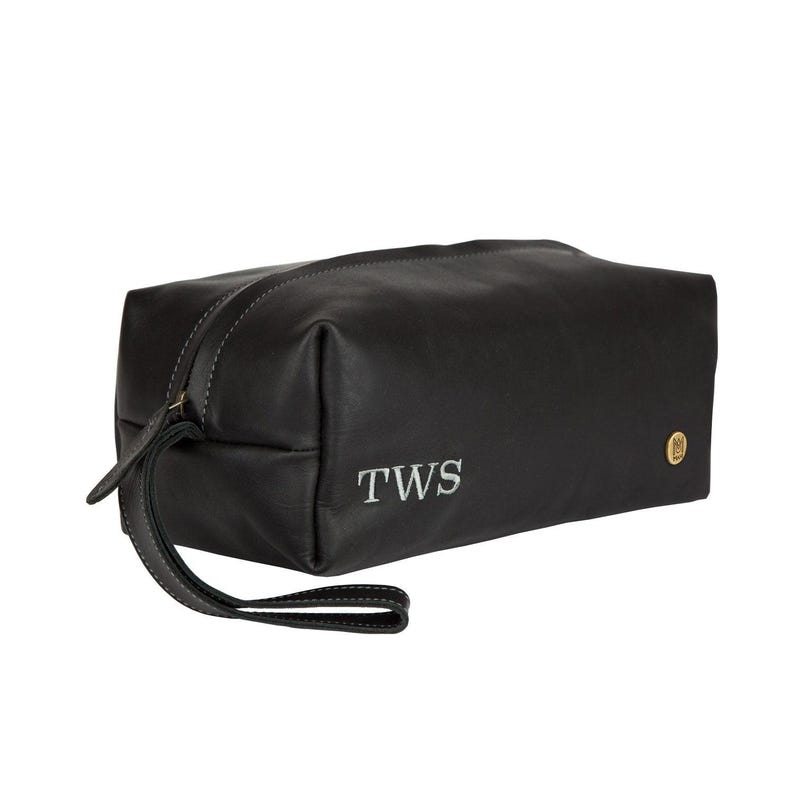 Puede incluir: Bolsa de viaje de cuero negro con cierre de cremallera y asa superior. La bolsa tiene una inscripci&oacute;n monograma que dice "TWS".