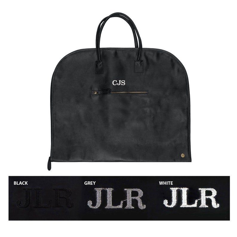 May include: Black garment bag with a zippered pocket and two handles. The bag has the initials "CJS" embroidered on the front. The bag is shown with three different monogram options: black, grey, and white.