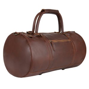 May include: A brown leather duffel bag with two top handles and a zippered closure. The bag has a front pocket with a zipper.