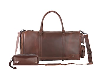 May include: A brown leather duffel bag with a matching brown leather toiletry bag. The duffel bag has a top handle and a shoulder strap. The toiletry bag has the initials "CJS" embossed on the front.