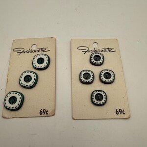 May include: Two rectangular beige cards labeled Fashionette, each holding square buttons with rounded corners. The buttons are dark green with a white border featuring a dashed black line pattern. Each card displays the price 69 cents.