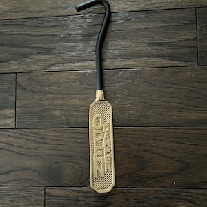 May include: A gold-colored metal damper pull with a black handle. The pull has the words "OPEN" and "DAMPER" embossed on it.