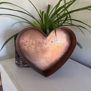 May include: A heart-shaped copper tray with a hammered finish. The tray is sitting on a woven basket.