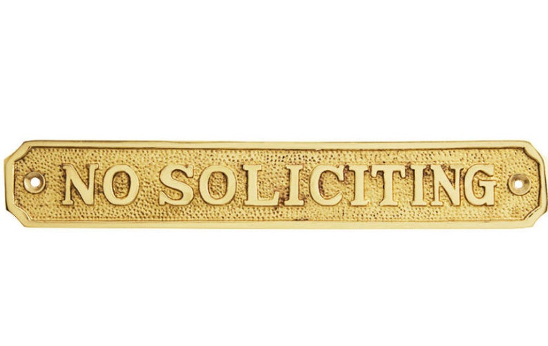 May include: A rectangular brass sign with the words "NO SOLICITING" in raised lettering. The sign has a textured background and decorative edges, with holes for mounting.