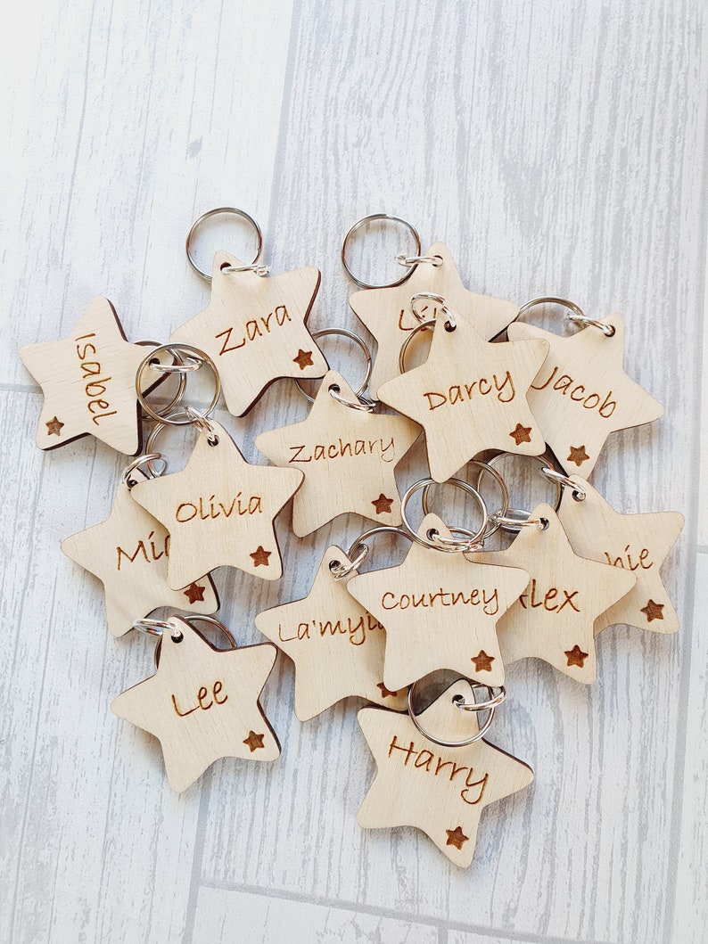 Peut inclure: Un ensemble de porte-cl&eacute;s en bois en forme d'&eacute;toile avec diff&eacute;rents noms grav&eacute;s dessus, notamment "Zara", "Darcy", "Jacob", "Olivia", "Lee", "Harry", "Courtney", "Flex", "La'mya", "Zachary", "Isabel" et "Ni&eacute;".