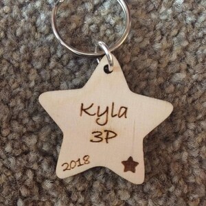Peut inclure: Un porte-cl&eacute;s en bois en forme d'&eacute;toile avec le nom "Kyla 3P 2018" grav&eacute; dessus.