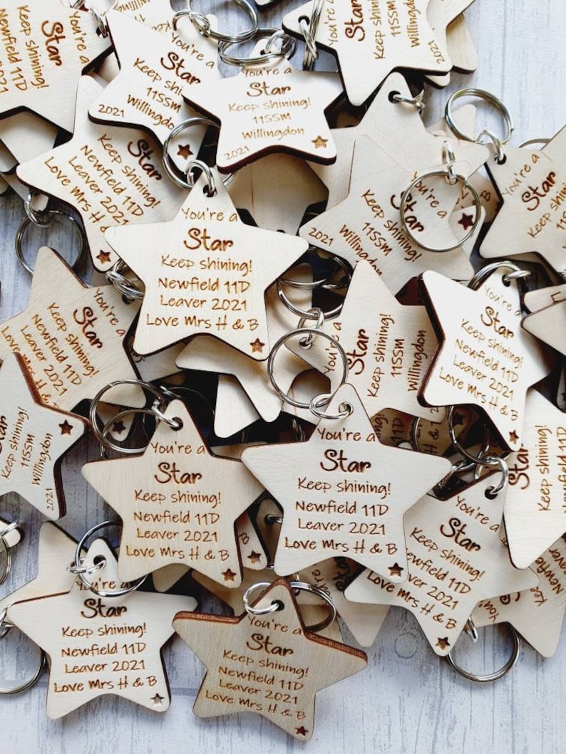 Peut inclure: Un tas de porte-cl&eacute;s en forme d'&eacute;toile en bois avec le texte "You're a Star Keep shining! Newfield 11D Leaver 2021 Love Mrs H & B" grav&eacute; dessus.