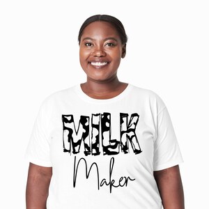 May include: White t-shirt with black text that says "MILK Maker" in a stylized font. The letters are filled with a black and white cow print pattern.