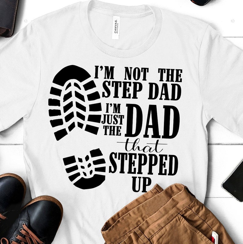 May include: White t-shirt with a black graphic design. The graphic features a footprint with the text "I'm not the step dad I'm just the dad that stepped up".