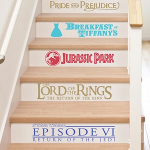 May include: A set of six movie title decals for stairs. The decals are in various colors and feature the titles "Black Swan", "Pride and Prejudice", "Breakfast at Tiffany's", "Jurassic Park", "The Lord of the Rings: The Return of the King", and "Star Wars: Episode VI - Return of the Jedi".