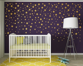 May include: A white crib with a yellow mattress and pillows sits on a yellow patterned rug. The wall behind the crib is dark purple and decorated with gold star decals. A white floor lamp and a toy airplane are also in the room.