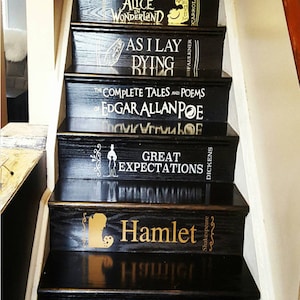 May include: Black wooden staircase with book titles painted on each step. Titles include "Pride and Prejudice," "Alice in Wonderland," "As I Lay Dying," "The Complete Tales and Poems of Edgar Allan Poe," "Great Expectations," "Hamlet," and "The Great Gatsby."