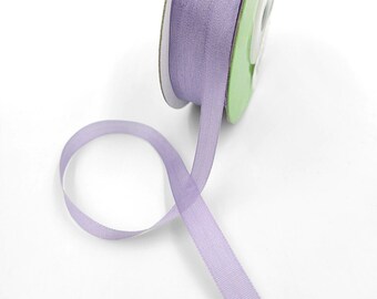 May include: A spool of lavender-colored ribbon with a light green cardboard spool. The ribbon is thin and has a subtle shimmer.