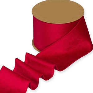 May include: A spool of bright red velvet ribbon. The ribbon is rolled on a cardboard spool and is ready to be used for crafting, gift wrapping, or decorating.