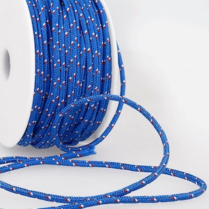May include: A spool of blue cord with white and red dots. The cord is wound around a white spool and a length of cord is hanging off the spool.