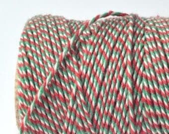 May include: A spool of red, white, and green baker's twine. The twine is twisted and has a striped pattern.
