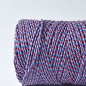 Peut inclure: Une bobine de ficelle de boulanger bleue et rouge. La ficelle est torsadée et présente un motif rayé.