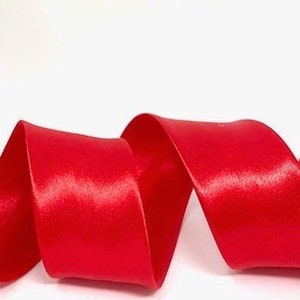 May include: A spool of bright red satin ribbon. The ribbon is curled and twisted, showing its smooth, shiny surface.