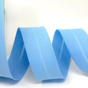 May include: A roll of light blue elastic fabric trim. The fabric is folded and curled, showing the texture of the material.