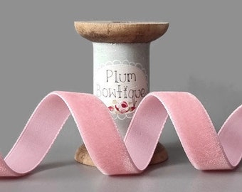 May include: Pink velvet ribbon wound around a wooden spool with a label that reads "Plum Boutique".