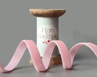 May include: Pink velvet ribbon wound around a wooden spool with a label that reads "Plum Boutique".