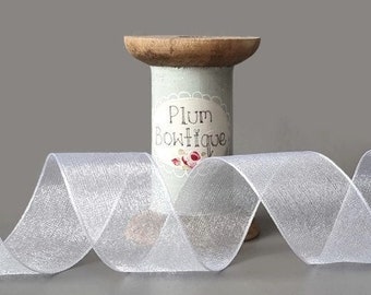 May include: A spool of silver glitter tulle ribbon. The ribbon is on a wooden spool with a label that reads "Plum Boutique".