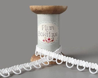 May include: White cotton trim with a scalloped edge, wound around a wooden spool labeled "Plum Boutique".