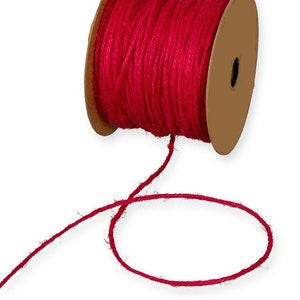 May include: A spool of bright red twine, wound around a cardboard core. The twine is made of natural fibres and has a slightly rough texture. A length of twine is unraveled and looped in the foreground.