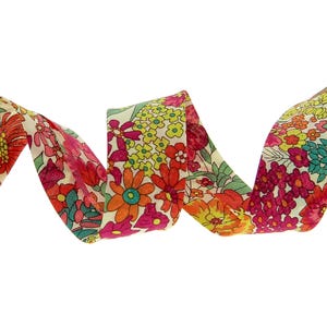 May include: A fabric ribbon featuring a dense, colorful floral pattern on a cream background. The design includes various small flowers in shades of bright pink, orange, yellow, and teal, arranged in a continuous, repeating botanical print.