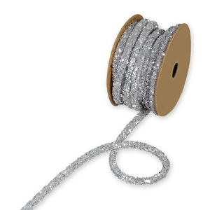 May include: A reel of silver glitter ribbon. The ribbon is wound on a cardboard reel. The ribbon is unraveled and looped, showing the texture and sparkle of the glitter, perfect for crafts.
