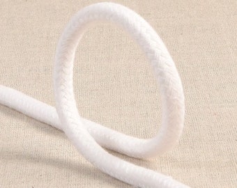 Puede incluir: Cordón de algodón blanco, una cuerda gruesa y suave con una textura lisa. El cordón está anudado en un círculo, mostrando su flexibilidad y durabilidad.