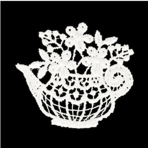 Könnte beinhalten: Weiße Spitzen-Teekanne mit Blumenmuster. Die Teekanne ist mit filigranen Spitzen verziert und hat einen Henkel und einen Ausguss.