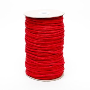 May include: A spool of red cord wound around a cardboard tube.