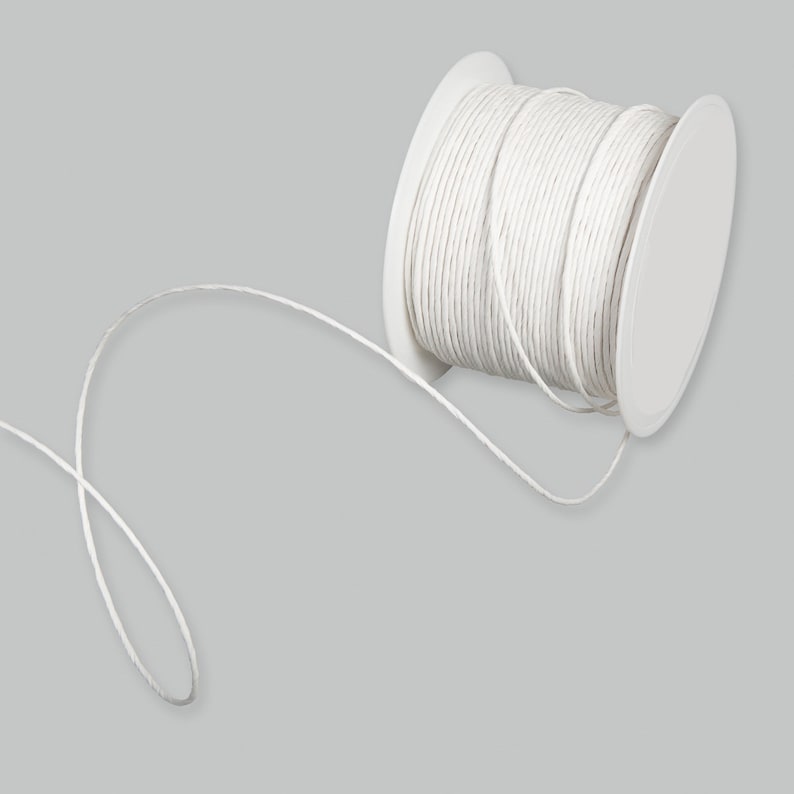 May include: A spool of white baker's twine with a length of twine extending from the spool.