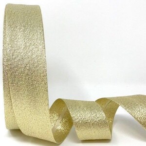 May include: A roll of gold glitter ribbon with a subtle shimmer. The ribbon is flat and has a woven texture.