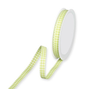 May include: A spool of green and white gingham ribbon. The ribbon is on a white spool and is curled.
