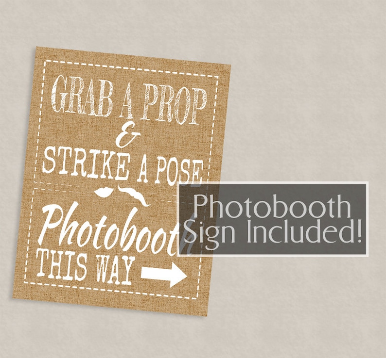May include: A brown burlap sign with white text that reads "Grab a prop & strike a pose Photobooth this way" with a white arrow pointing to the right. The sign also includes a white mustache and lips graphic. The text "Photobooth Sign Included!" is in a gray box on the sign.