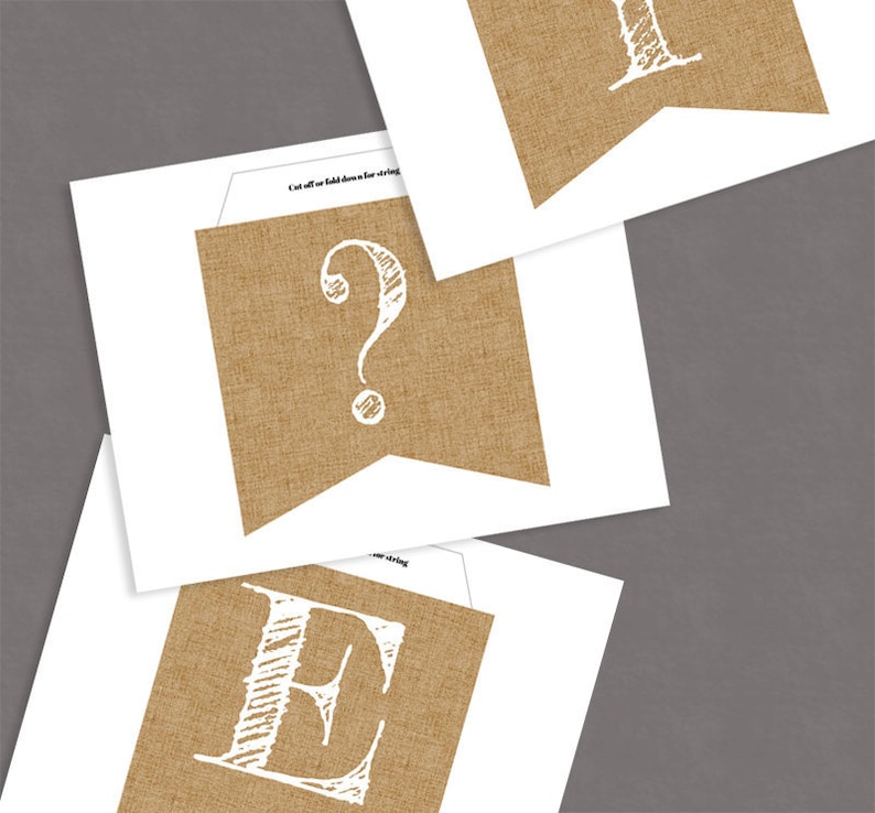 K&ouml;nnte beinhalten: Ein bedruckbarer Jutebanner mit den Buchstaben "E" und "?" in Wei&szlig;. Die Buchstaben sind in handschriftlicher Form und befinden sich auf einem braunen Jutehintergrund.