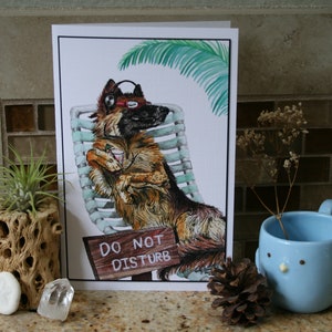 May include: A watercolor illustration of a dog wearing headphones and sunglasses, relaxing in a lounge chair with a drink. The dog is brown and black with a white chest. The background is a white card with the text "Do Not Disturb" on a wooden sign.