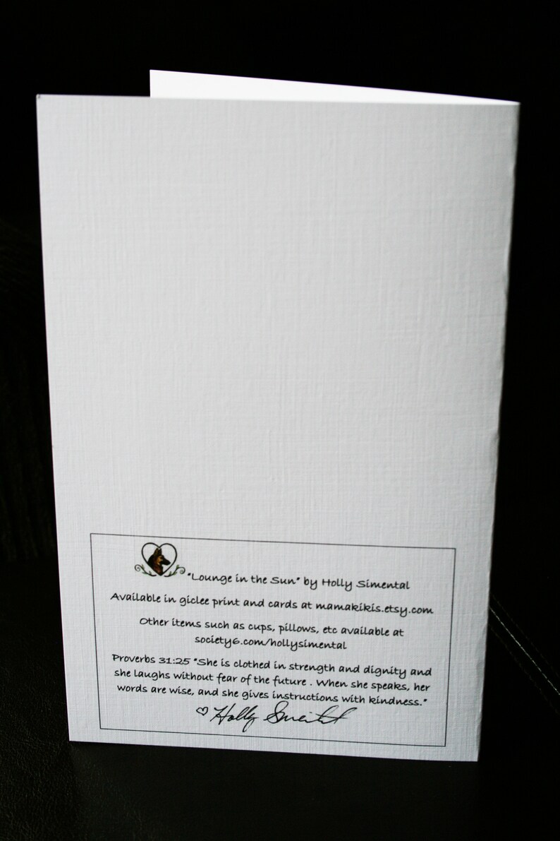May include: A white card with a black and white illustration of a dog's head in a heart shape. The text on the card reads "Lounge in the Sun" by Holly Simental. Available in giclee print and cards at mamakikis.etsy.com. Other items such as cups, pillows, etc available at society6.com/hollysimental. Proverbs 31:25 "She is clothed in strength and dignity and she laughs without fear of the future. When she speaks, her words are wise, and she gives instructions with kindness."  ♡ Holly Smith