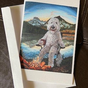 Tarjeta de arte grande en blanco con un labradoodle campadoodle tomando café junto a una fogata